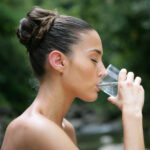 Frau trinkt Wasser aus Glas im Freien