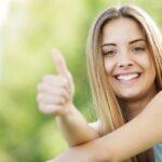EMF-Schutz, Frau gibt Daumen hoch, natürliche Umgebung, Elektrosmog verhindern, handliche EMF-Absorber, gesundes Leben, elektromagnetische Felder schützen, persönliche EMF-Filtration.