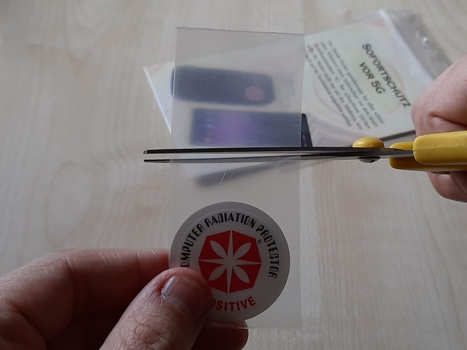 EMF-Schutzstickers gegen elektromagnetische Strahlung, Test mit Schere und positiver Reaktion, für gesunden Schlaf und Schutz vor Elektrosmog, praktische Anwendung im Alltag.
