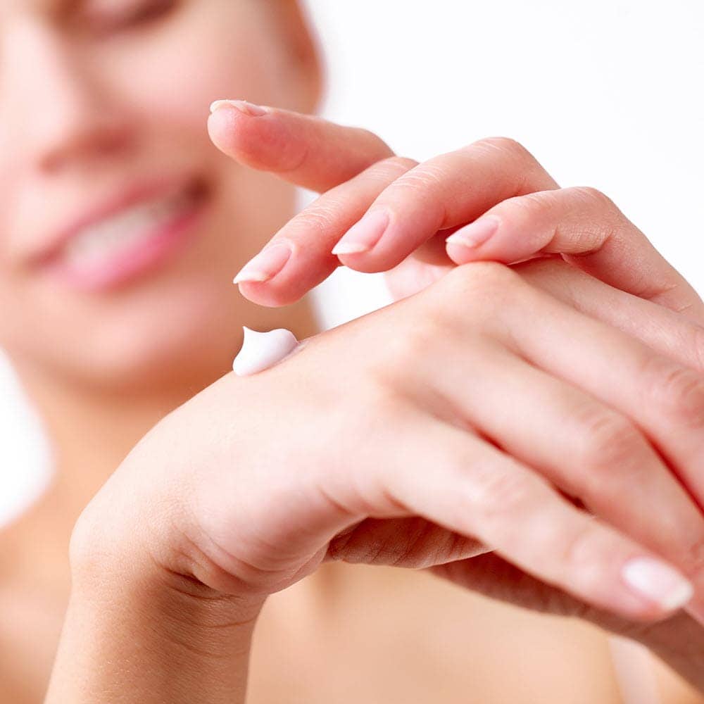 Soin de la peau avec protection EMF, femme appliquant de la crème sur sa peau, protection naturelle contre les radiations électromagnétiques, quotidien, santé, environnement minimaliste.