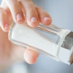 Zoutstrooier in de hand, natuurlijke ondersteuning voor EMF-bescherming, gezonde levensstijl, ontgifting en welzijn.