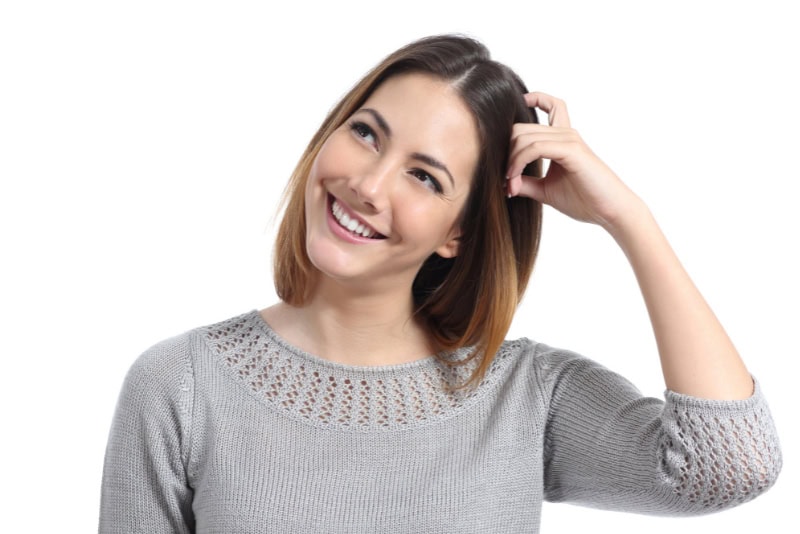Mujer reflexiona mientras se toca el cabello, simbolizando la conciencia sobre los campos electromagnéticos y la protección contra la exposición a EMF.