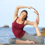 Entspannende Frau beim Yoga am Strand, fördert Wohlbefinden und Balance, ideal für Stressabbau und Gesundheit.