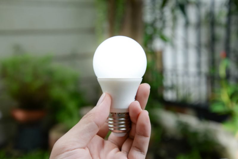 Main tenant une lampe LED écoénergétique, la solution d'éclairage innovante pour une maison et un bureau durables, réduit les champs électromagnétiques (EMF) et la consommation d'énergie.