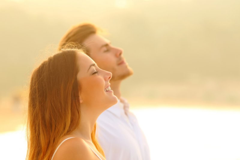 Coppia felice sulla spiaggia respira aria fresca, simbolo di salute e benessere grazie alla protezione EMF.